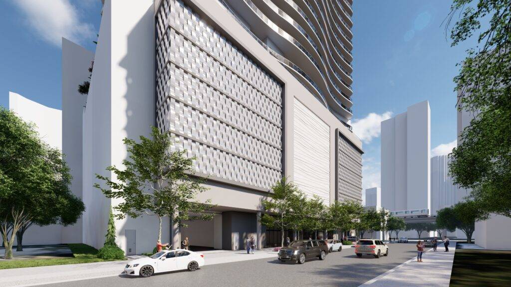 Modern high-rise building with a sleek facade on a busy urban street, surrounded by trees and vehicles.