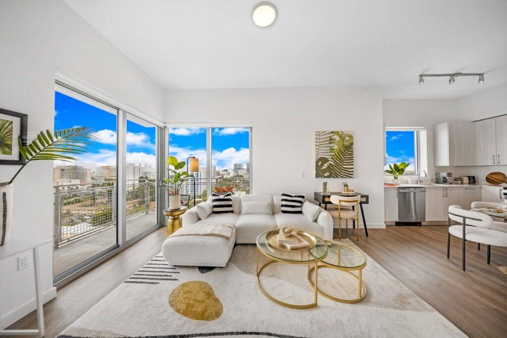 Modern living room with white furniture and large windows overlooking a cityscape.