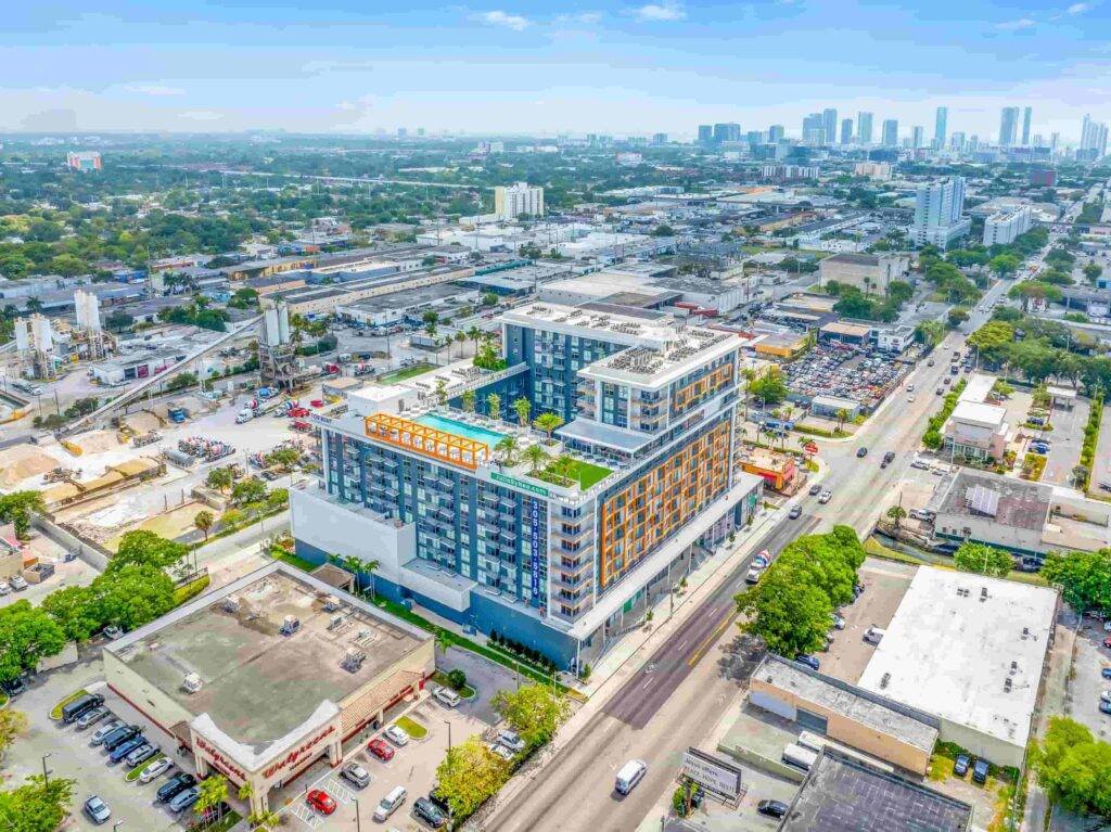 Aerial view of a modern urban building surrounded by cityscape and greenery.