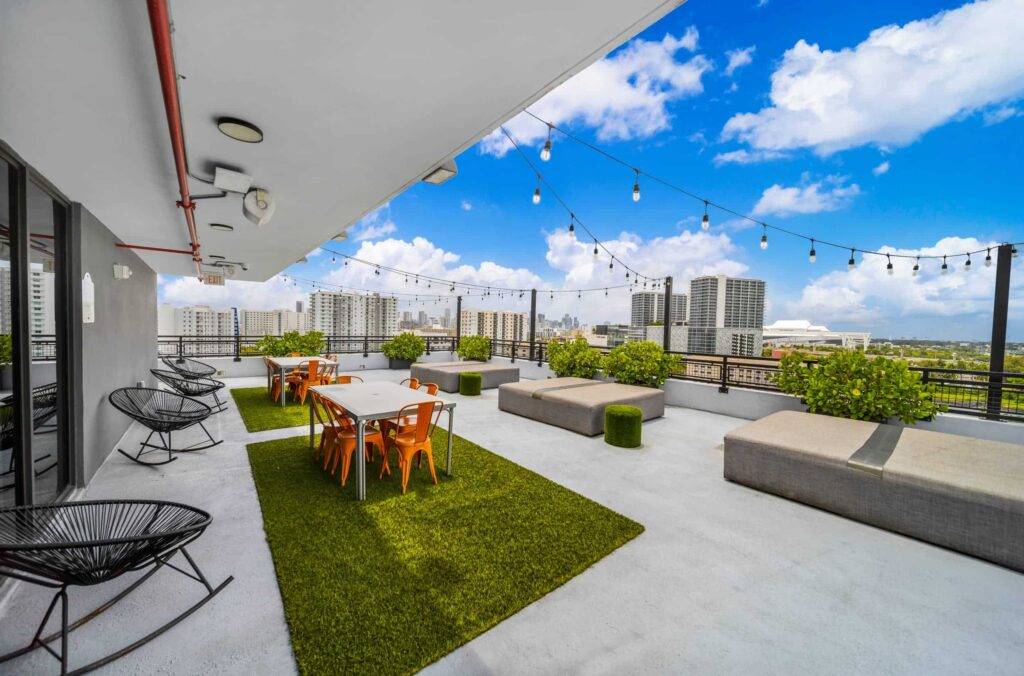 Rooftop terrace with modern seating and vibrant city skyline under a bright blue sky.