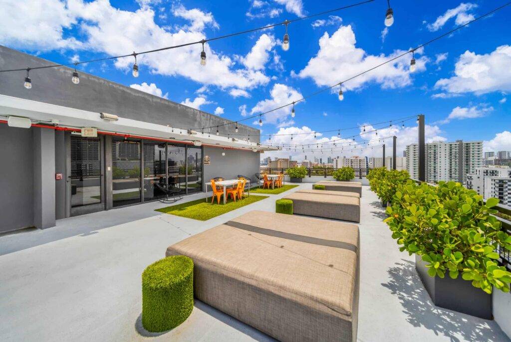 Rooftop terrace with plush seating, string lights, and city skyline.
