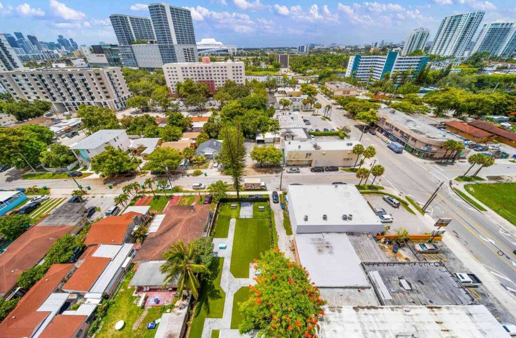 Aerial view of Allapattah neighborhood with modern skyscrapers in the background and lush greenery.