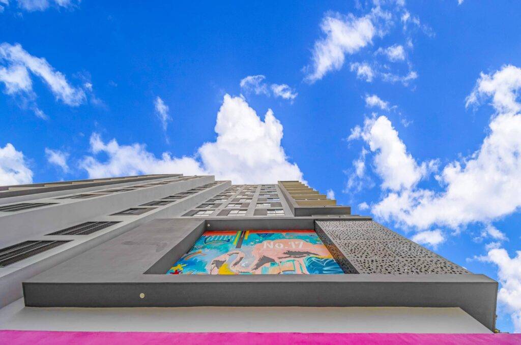 Modern building with colorful mural against a bright blue sky with clouds