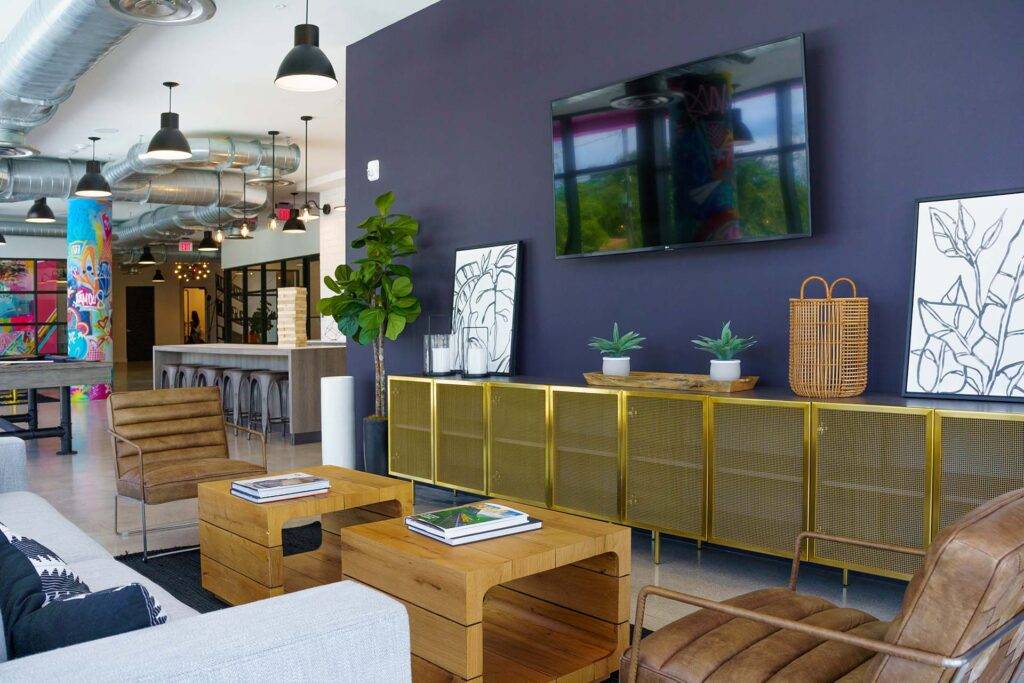 Modern living room with stylish wooden furniture, a dark accent wall, and contemporary artwork.