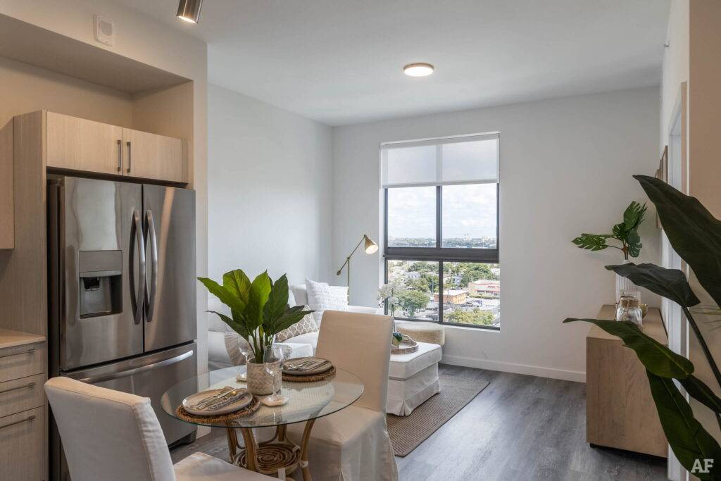 Modern apartment interior with cozy seating, dining set, and large window view.
