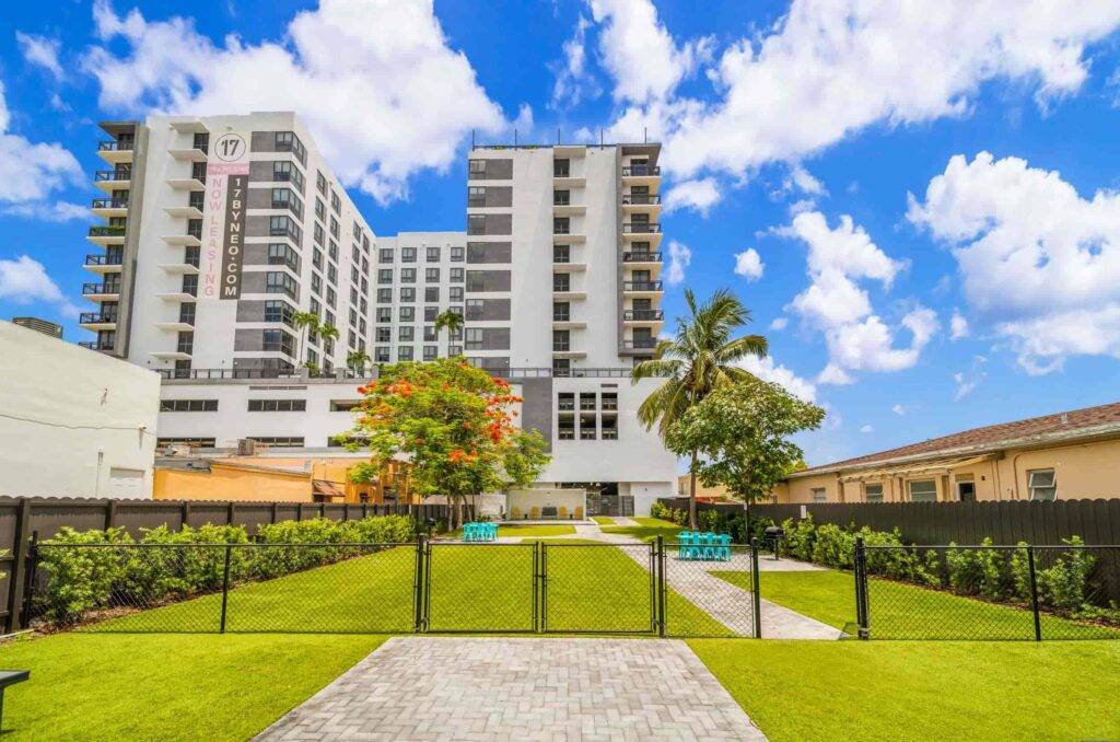 Modern apartment complex under a vibrant blue sky with lush green lawns.
