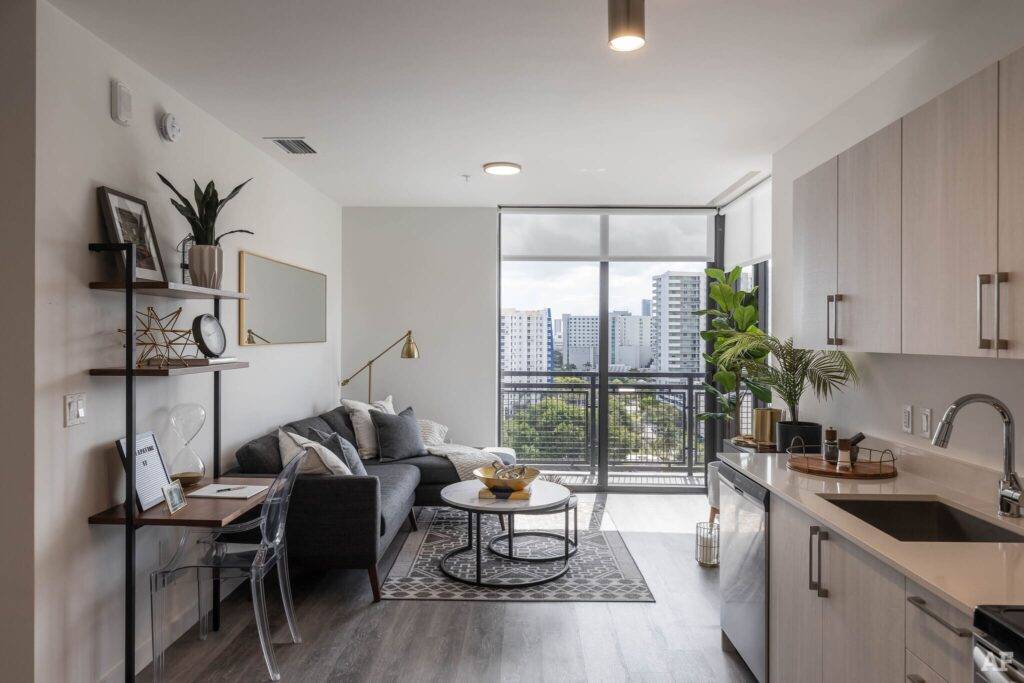 Modern apartment interior with a cozy living room, sleek kitchen, and large windows overlooking cityscape.