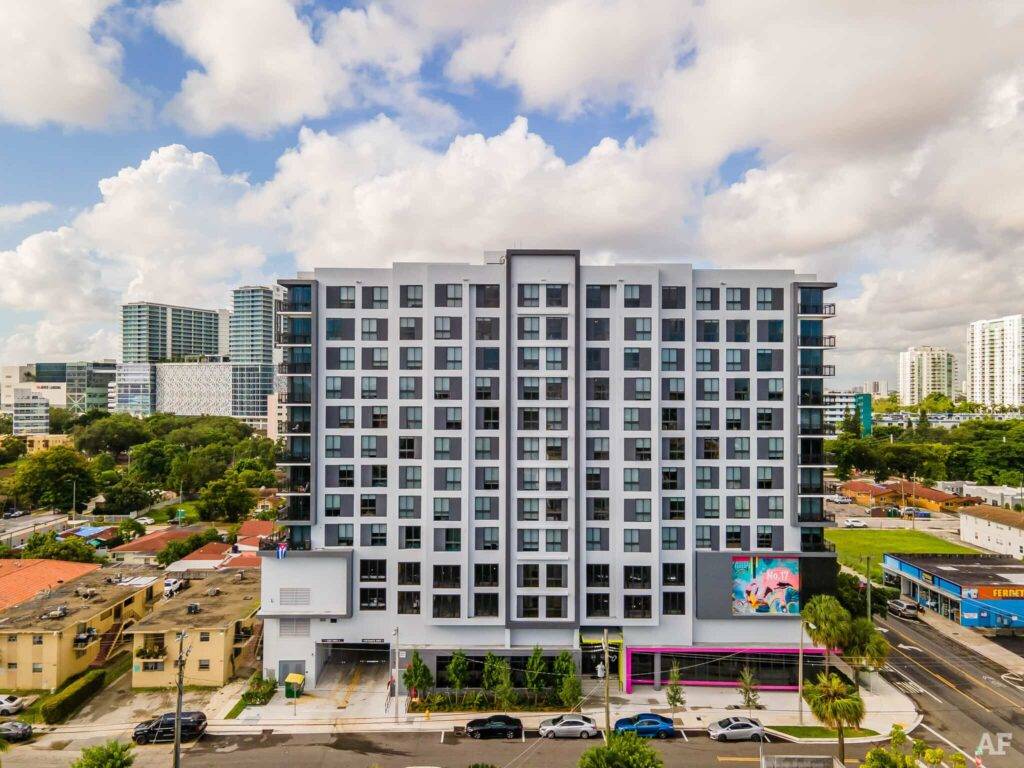 Modern high-rise building in Allapattah with vibrant mural and city skyline.