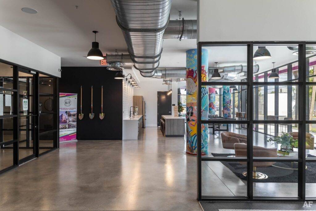 Modern industrial-style office interior with glass partitions and vibrant wall art.
