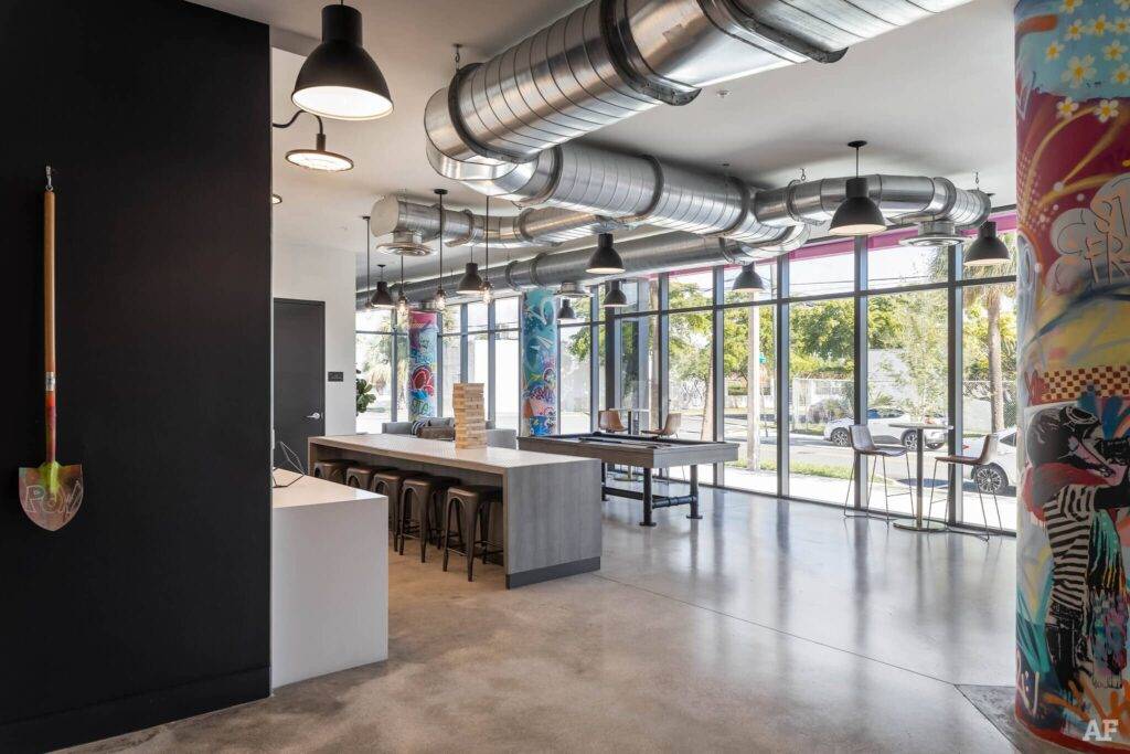 Modern industrial interior with ductwork, colorful columns, and large windows.