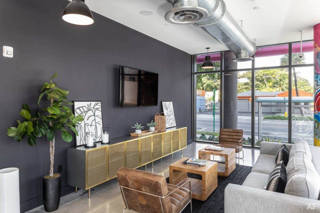 Modern living room with industrial decor featuring brown leather chairs, a sleek cabinet, and a large TV.