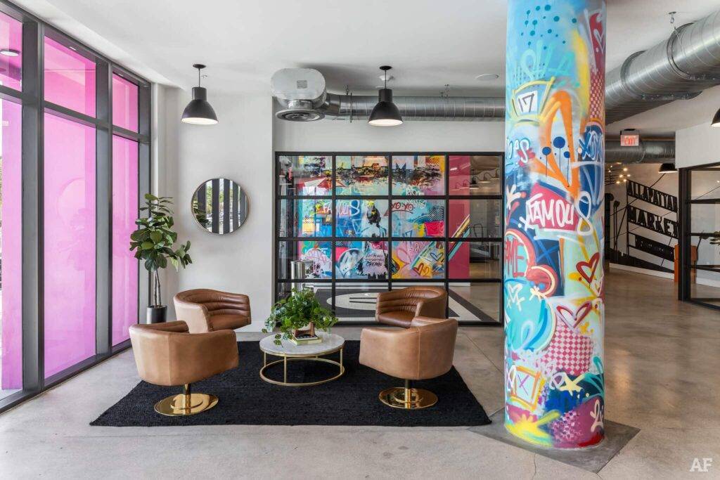 Vibrant modern office lobby with colorful graffiti pillar, leather chairs, and artistic wall panels.