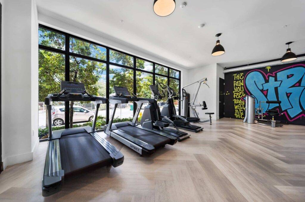 Modern gym with treadmills and vibrant graffiti wall.