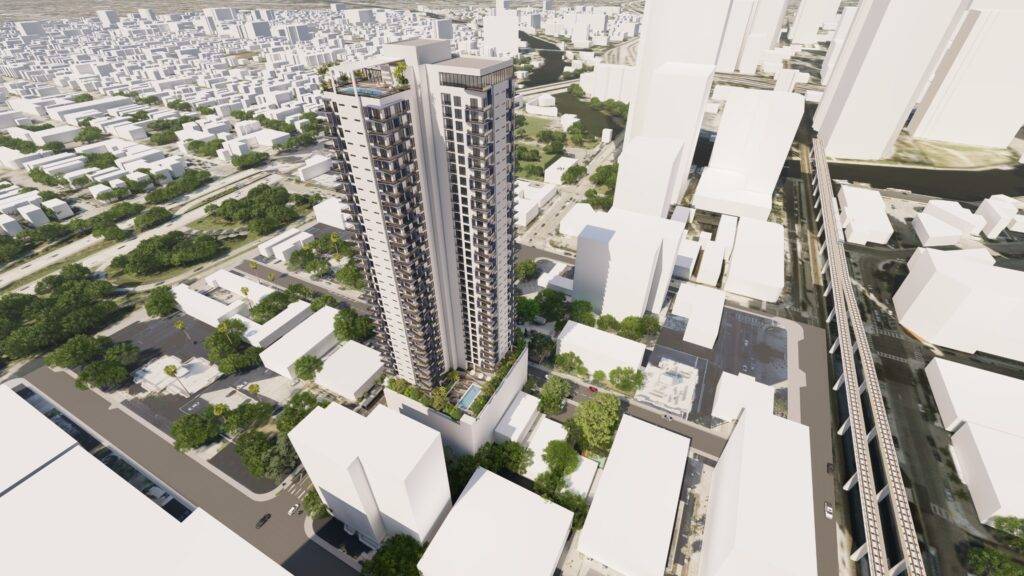 Aerial view of a tall, modern skyscraper surrounded by city buildings and green spaces, showcasing urban architecture.