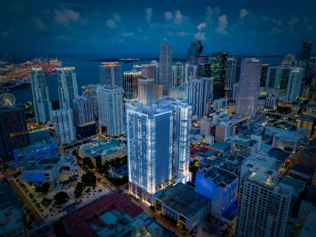 Aerial view of a vibrant cityscape at night, featuring illuminated skyscrapers and city lights.