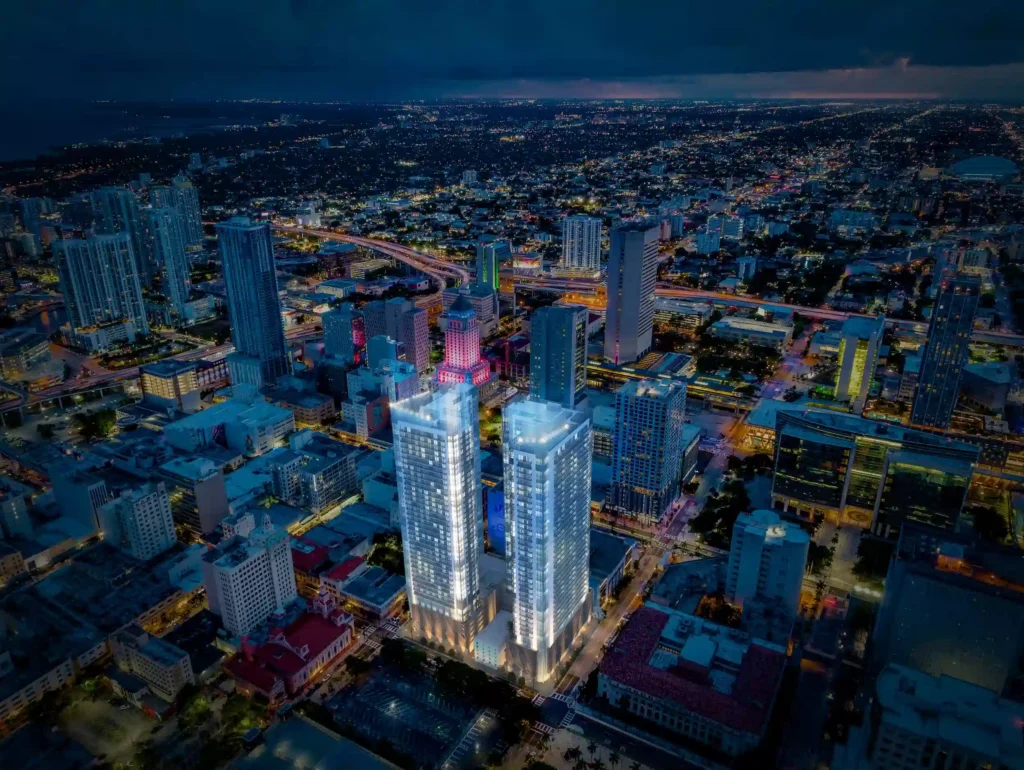Night aerial view of illuminated skyscrapers in a bustling cityscape.