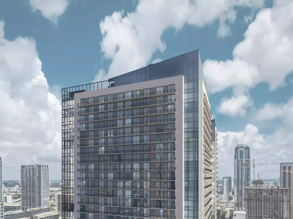 Modern skyscraper with glass facade under a cloudy sky in an urban setting.