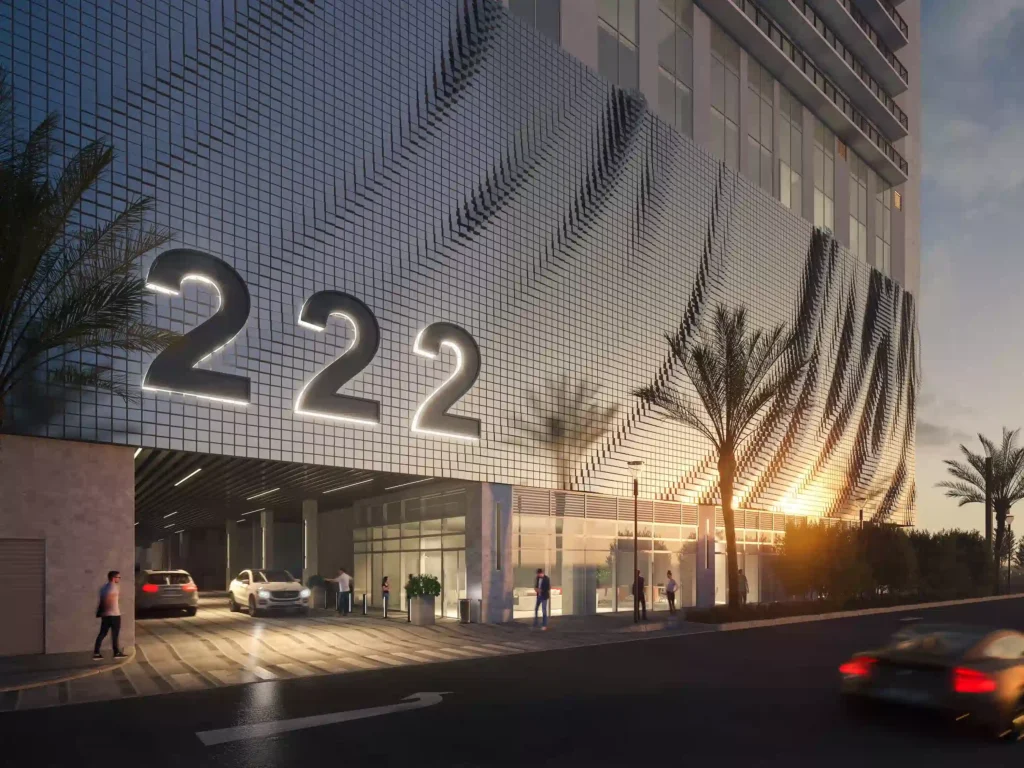 Modern building with illuminated "222" sign and palm trees at sunset.