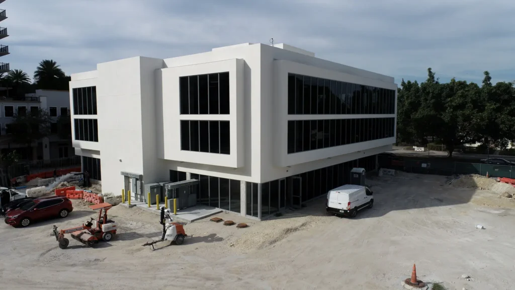 Modern white office building with large windows and construction site.