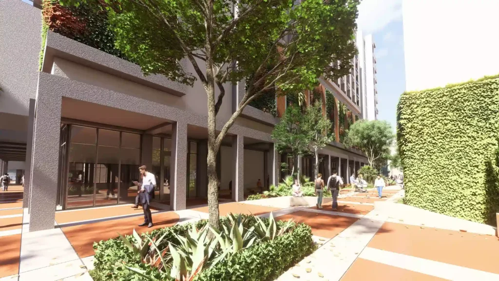 Modern urban landscape with lush greenery and a pedestrian walkway beside a contemporary building.