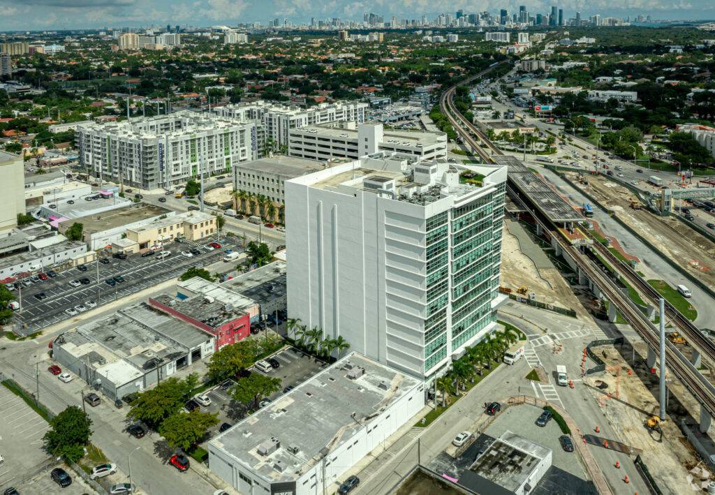 Aerial view of Coral Gables, featuring modern architecture, urban landscape, and city skyline in the distance.