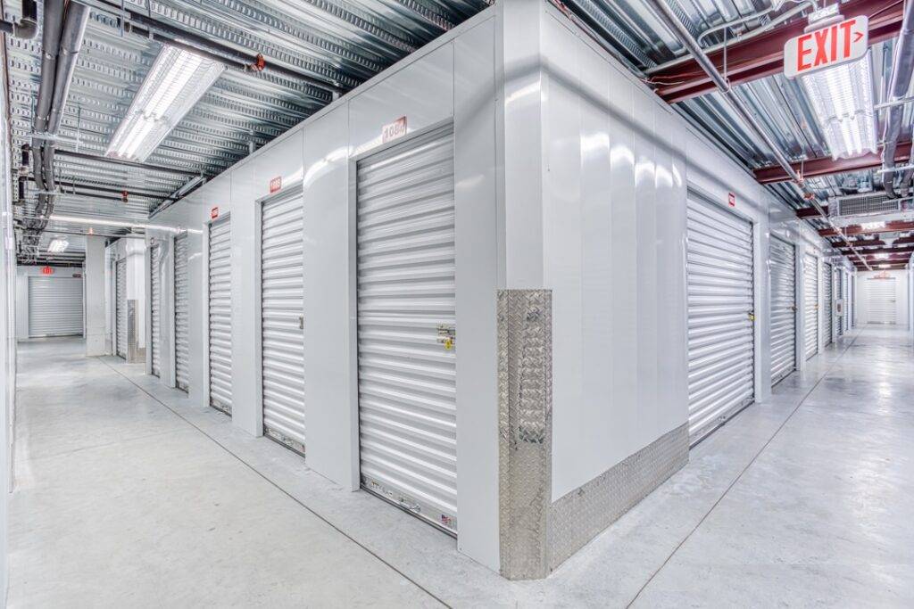 Modern indoor storage facility with white roll-up doors and bright lighting.