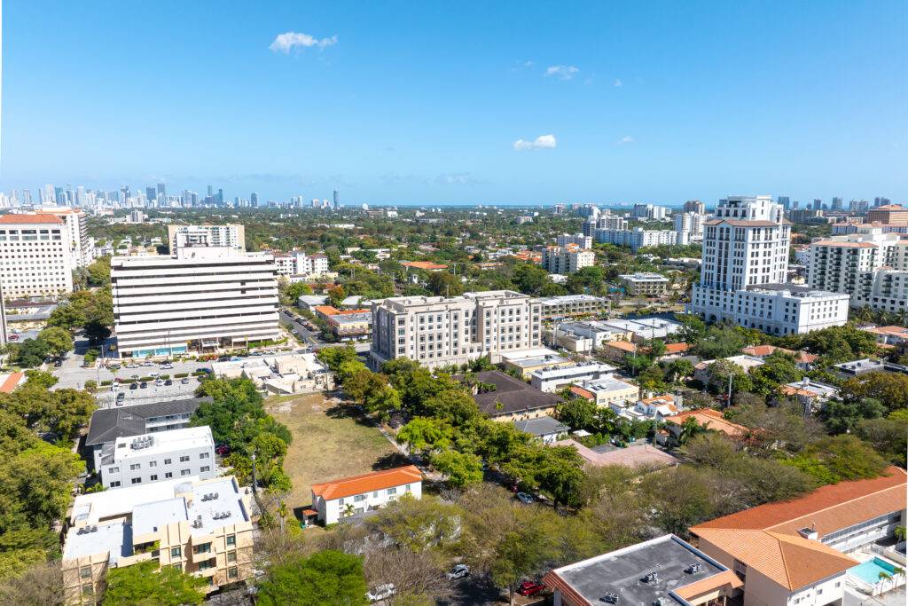 Aerial view of Coral Gables cityscape with high-rise buildings under a clear blue sky.