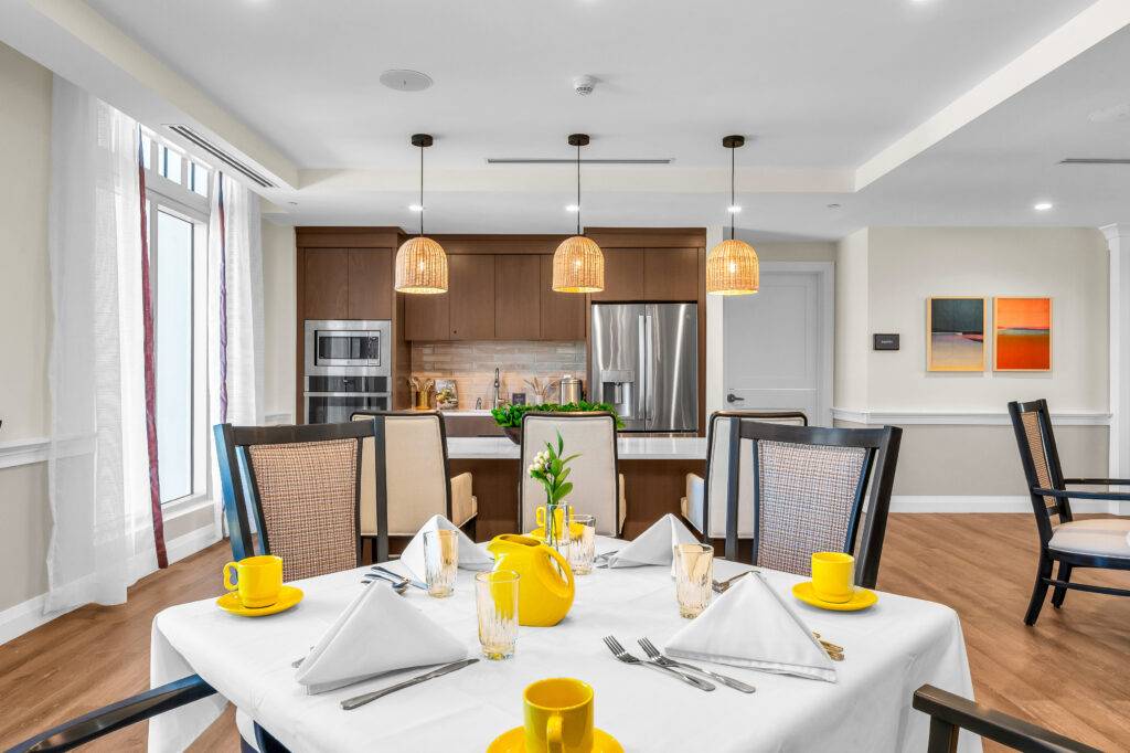 Elegant dining room with a table set for four, featuring yellow accents and modern lighting.