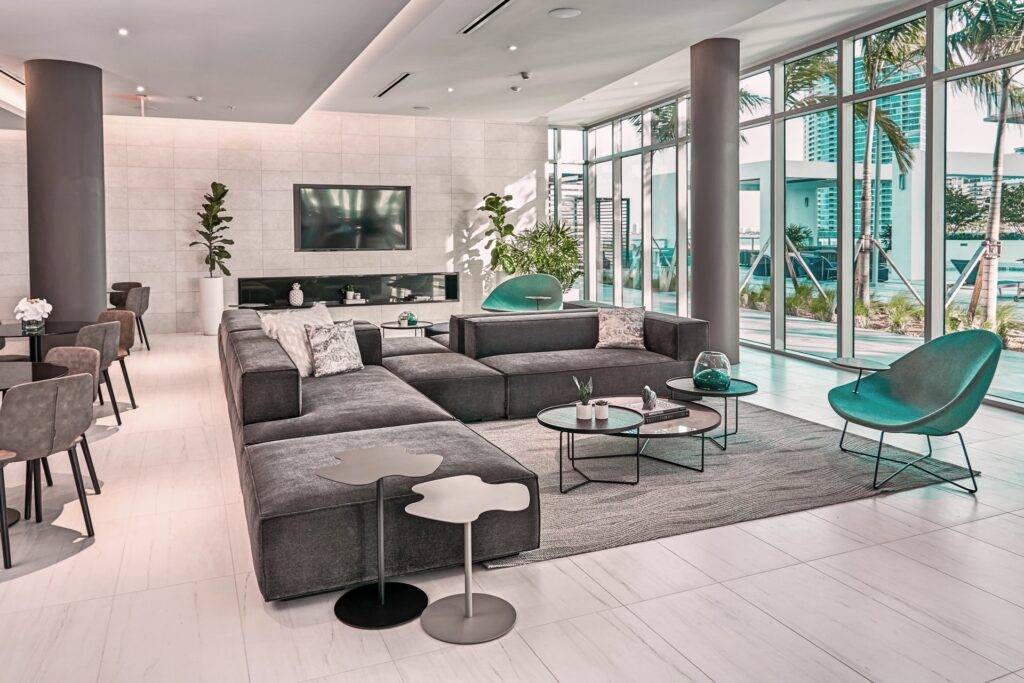 Modern living room with gray sectional sofa, sleek chairs, and large windows showcasing a bright, minimalist design.