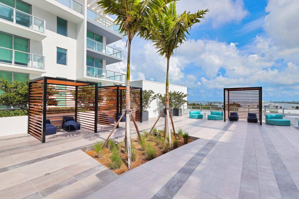 Modern rooftop patio with palm trees, lounge areas, and a stunning sky view.