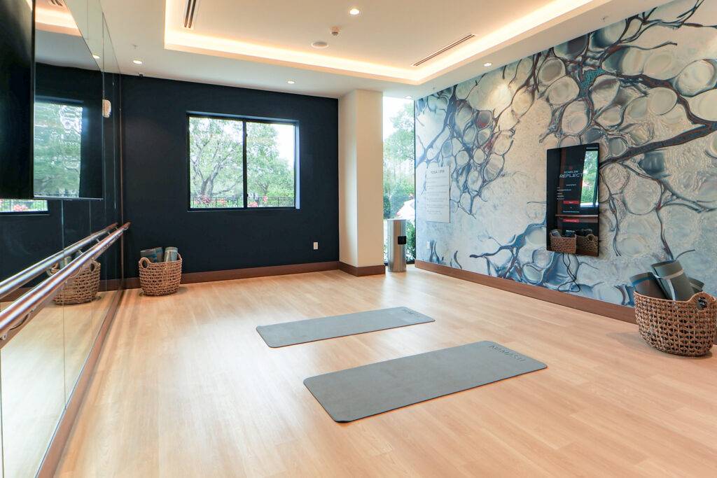 Modern yoga studio with wooden floors, two mats, wall art, and serene lighting.