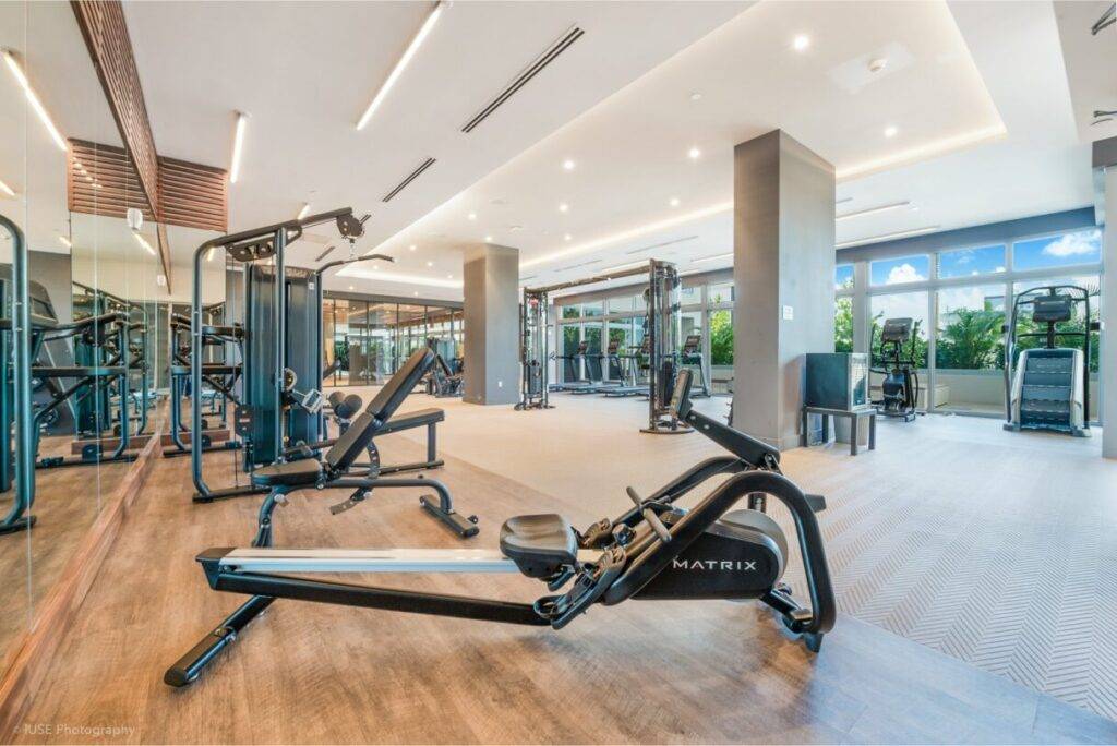 Modern fitness center with various exercise machines and bright natural light.