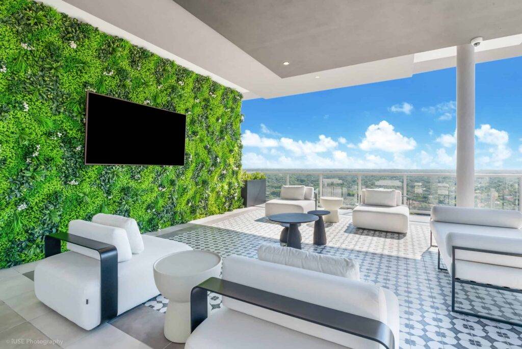 Luxurious modern rooftop terrace with green wall and stylish seating, overlooking a cityscape.