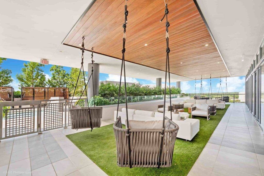 Modern outdoor lounge with hanging chairs and sleek design elements.