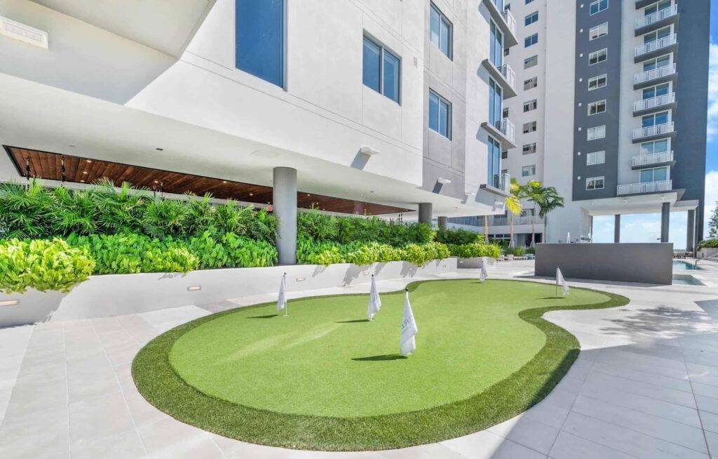 Modern building exterior with rooftop mini-golf course and lush greenery.