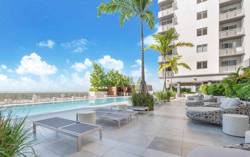 Rooftop pool with modern lounge area and cityscape views under a clear blue sky.