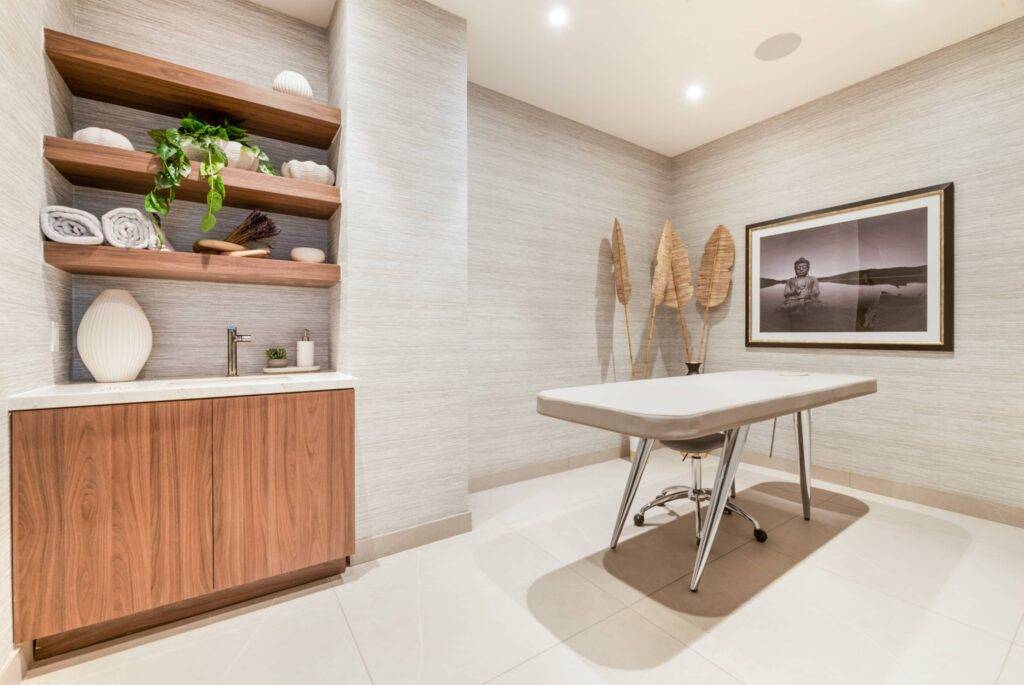 Modern therapy room with massage table and stylish decor, featuring wooden shelves and calm lighting.