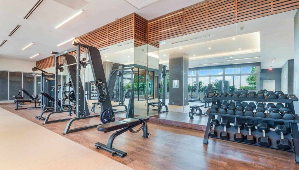 Modern gym with exercise machines, free weights, and large mirrors.