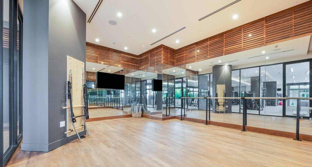 Spacious modern dance studio with wooden floors, mirrored walls, and bright lighting for ballet or fitness.