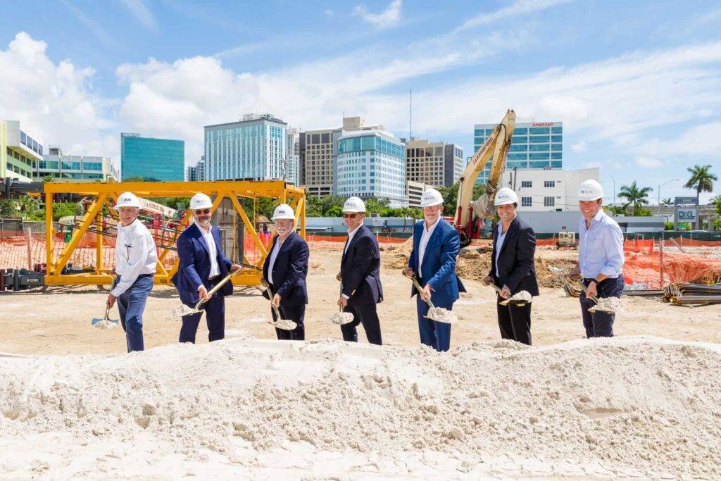 Construction team at groundbreaking ceremony with city skyline background.