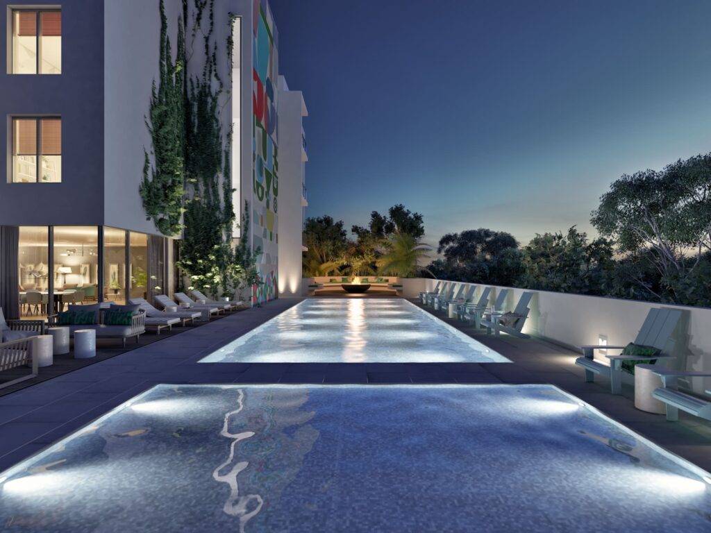 Modern rooftop pool illuminated at night with surrounding lounge chairs.