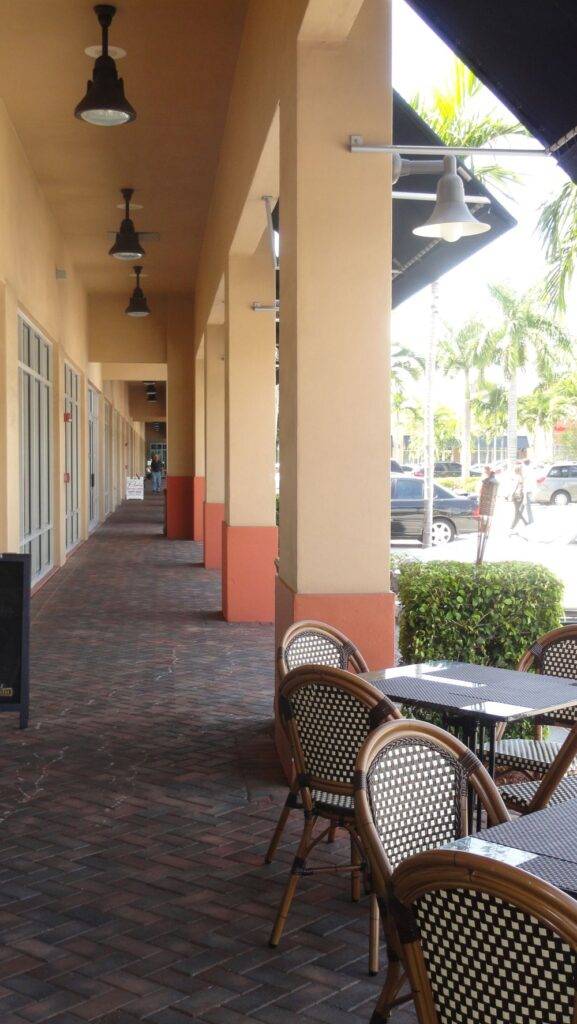 Outdoor view of Avanti Center with woven chairs and tables on a shaded brick walkway.