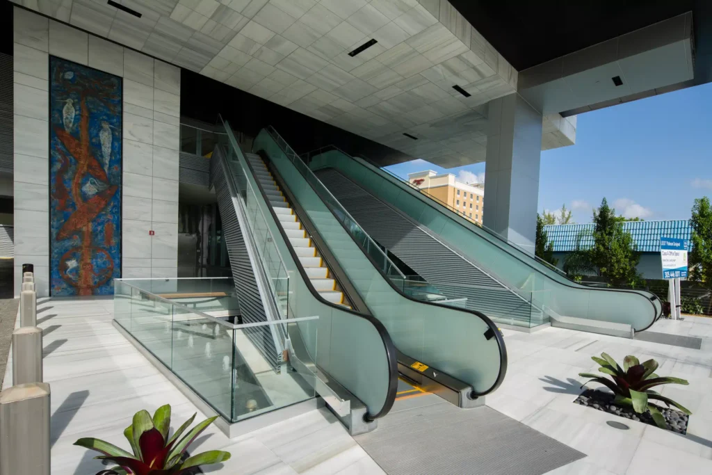 Modern escalators at Aventura Optima Plaza surrounded by sleek architectural design.