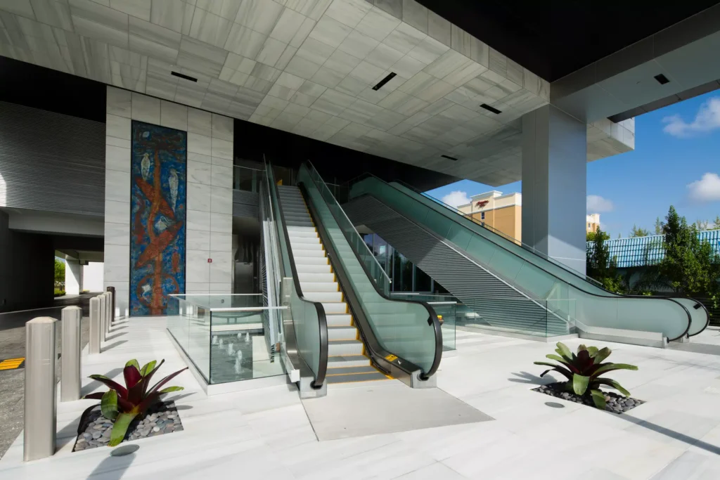 Modern plaza entrance with sleek escalators and artistic wall design.