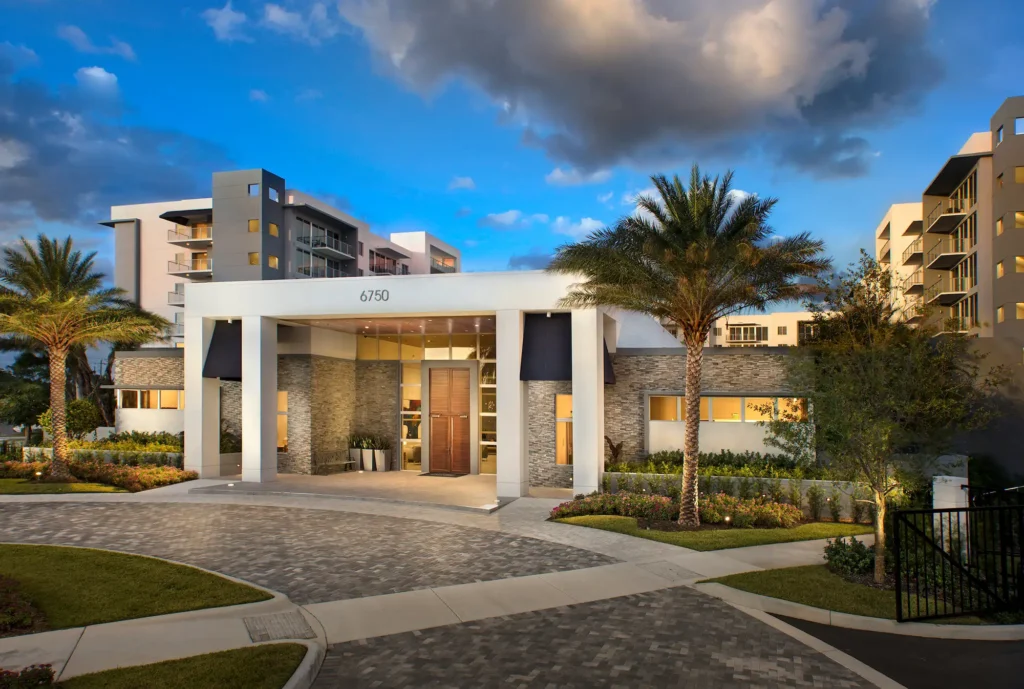 Modern apartment complex with palm trees and contemporary architecture under a vibrant sky.