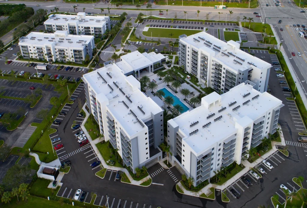 Aerial view of modern apartment complex with pool and parking lots in Boca Raton.