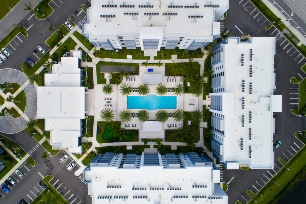 Aerial view of a modern apartment complex with a central pool and symmetrical design.