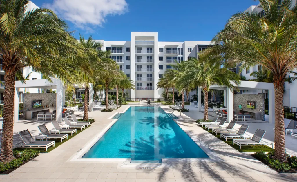 Luxurious apartment complex with palm trees and a modern pool area.