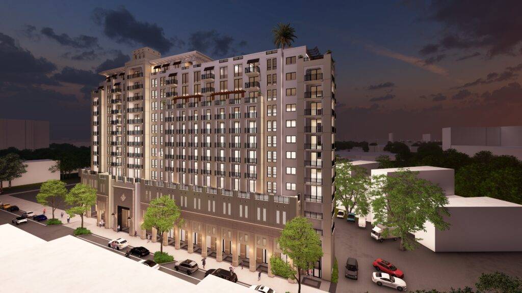 Modern high-rise building at dusk with illuminated windows and lush foliage surrounding it.