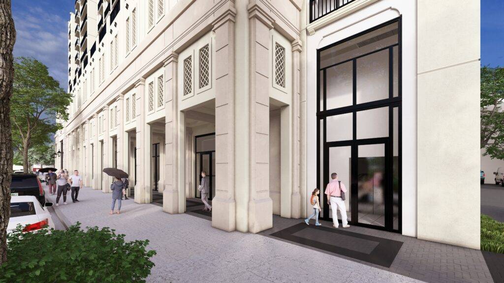 People walking outside a modern building with tall glass doors on a sunny day.